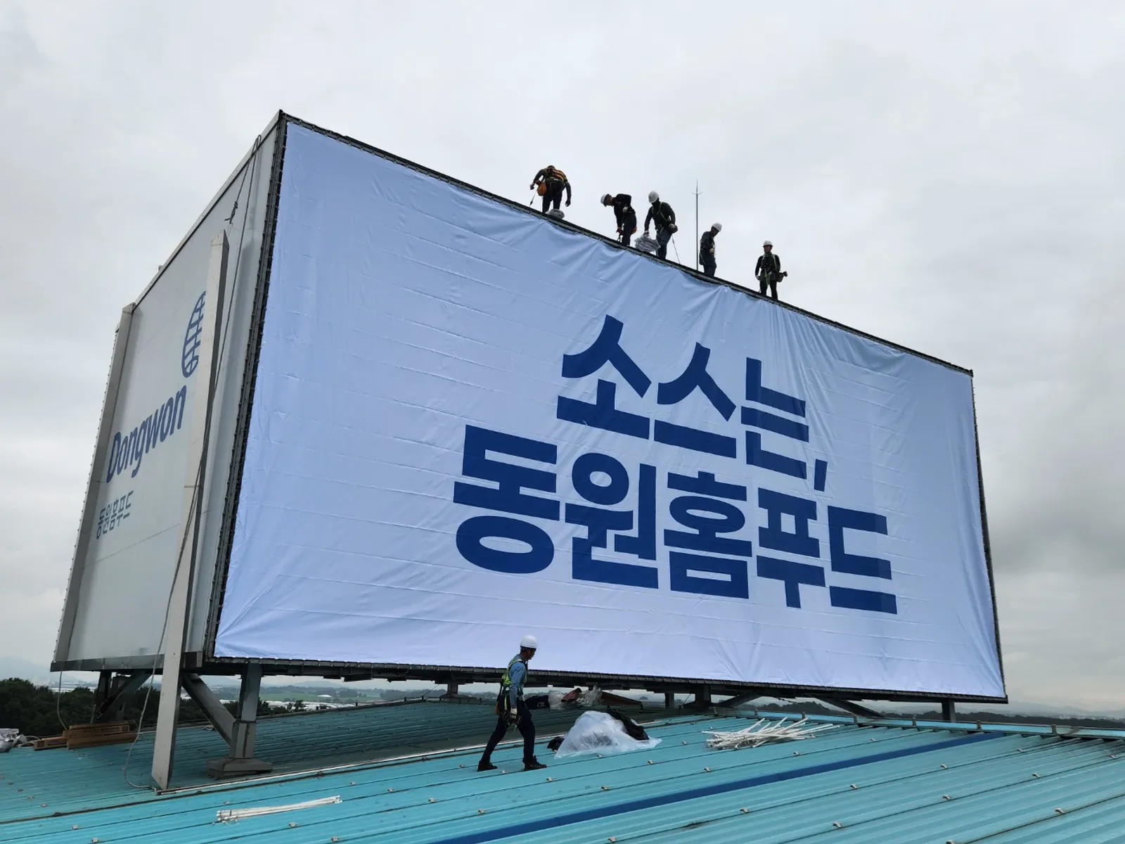 옥상 구조물에 대형 배접막(현수막)과 조명을 새로 교체하는 시공 현장