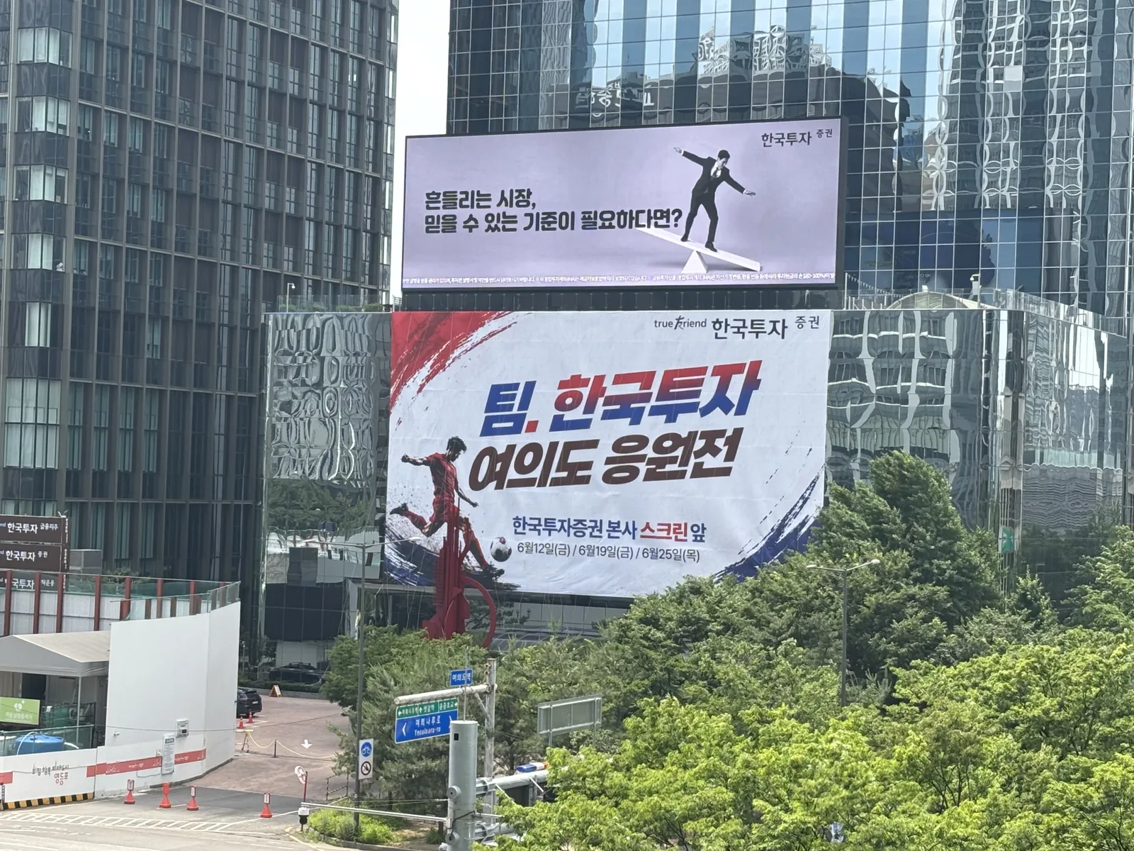 나무 너머로 보이는 빨간색과 파란색 대비 배색의 큰 글씨 문구 응원 현수막 전경