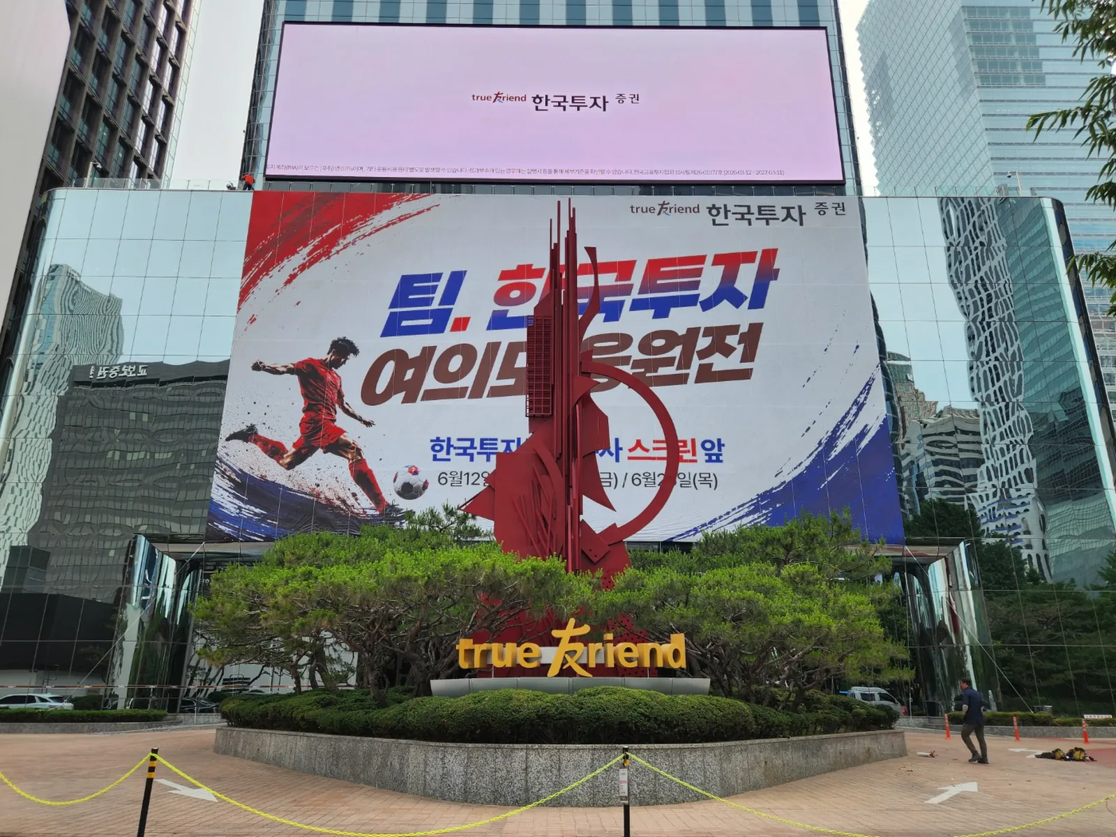 가로수와 화단 너머로 보이는 건물 외벽 대형 응원 현수막 전경
